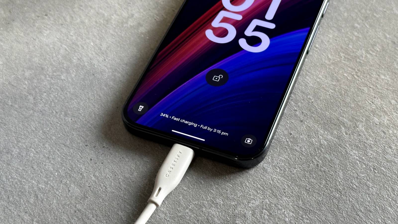 Uma mão segurando um smartphone com um ícone de bateria fraca no centro.