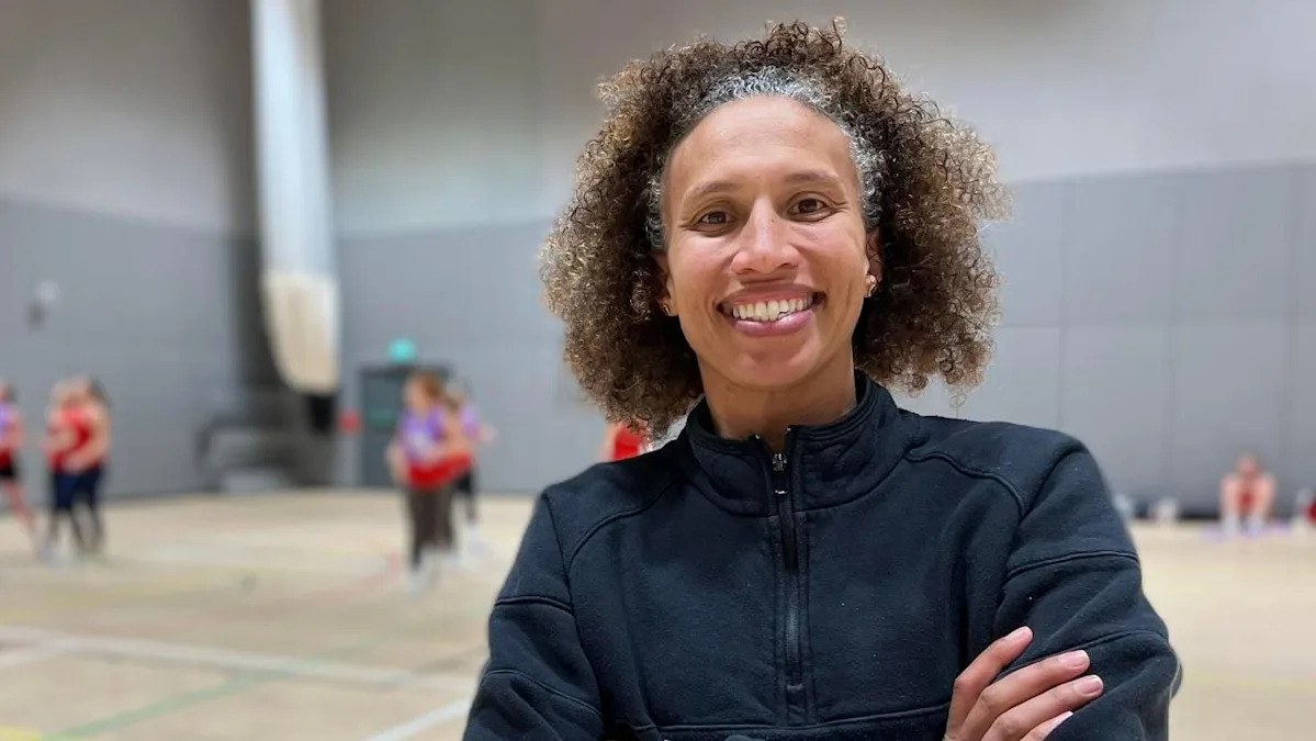 Serena Guthrie retratada em uma cena de ação jogando netball. Outro jogador está visível e Guthrie está ganhando a posse de bola.
