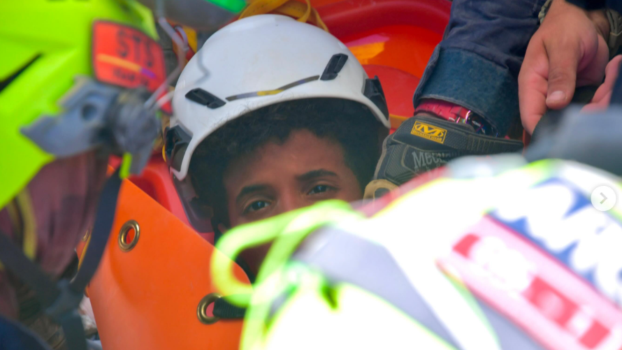 a imagem mostra metade do rosto dos meninos – o resto está obscurecido pelas equipes de resgate. Ele está usando um capacete branco e tem cabelo escuro e encaracolado.