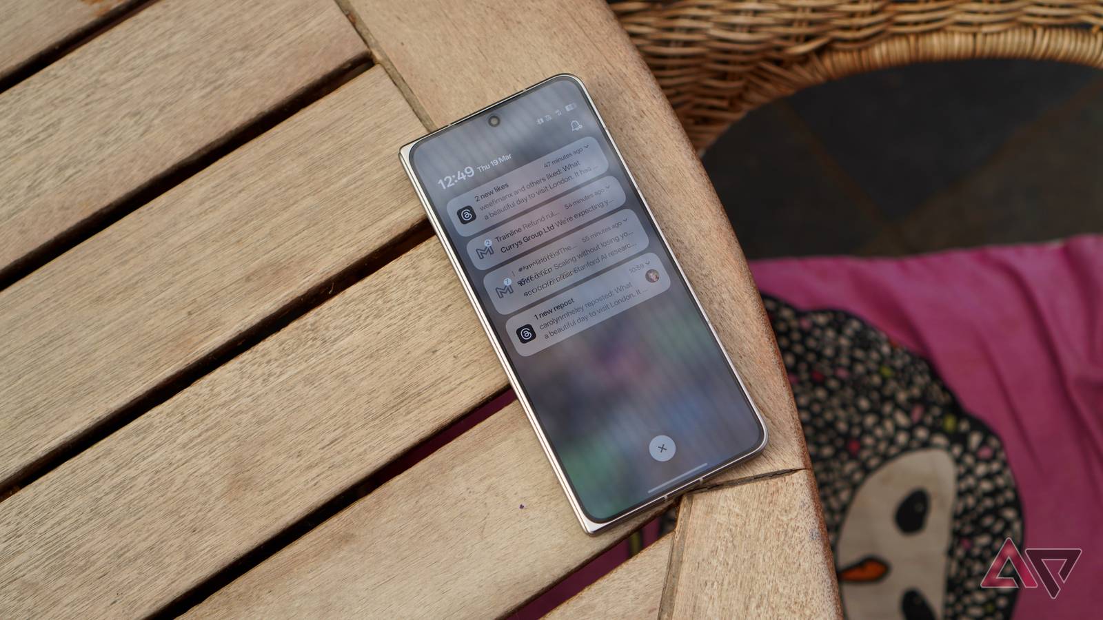 Mão segurando um smartphone com elementos interativos destacados na tela contra um fundo gradiente rosa com ícones brilhantes.