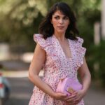 Alexandra Pereira usa brincos, uma ousada camisa oversized laranja neon / vermelha, mini shorts combinando, uma bolsa de couro tecido azul pastel claro da Bottega Veneta, sandálias de couro acolchoadas em tons pastéis claros da Bottega Veneta, em 20 de julho de 2021 em Paris, França.