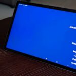 Dois smartphones Google Pixel colocados em uma superfície vermelha estilizada, um voltado para frente mostrando uma tela inicial minimalista e o outro mostrando a câmera traseira