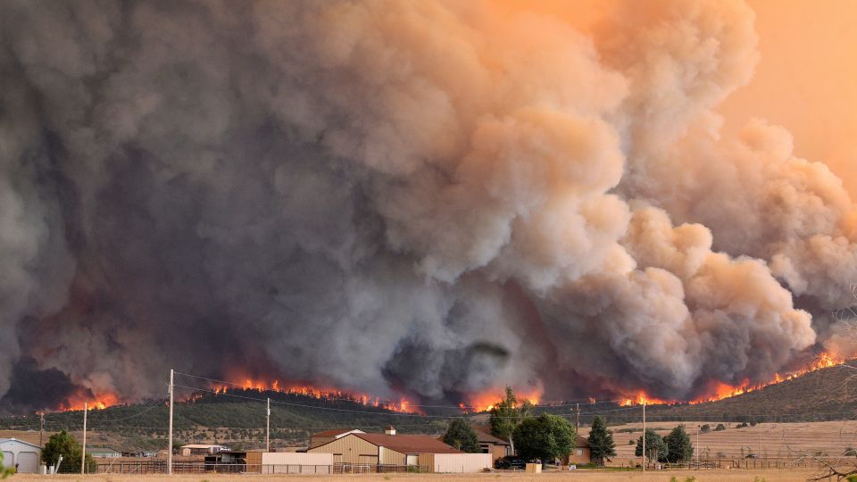 Uma mulher usa uma mangueira para umedecer a grama ao redor do parque de trailers Mountain Shadows Mobile Estates em Beulah, Colorado, em 29 de junho. - Jerilee Bennett/The Gazette/AP