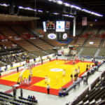 Vista interna de uma arena de basquete universitário durante um aquecimento de jogo, com quadra de madeira, placar, assentos para espectadores e fãs dentro do Fresno State Save Mart Center, na Califórnia. Investigação de apostas em Nevada leva à prisão em caso de basquete no estado de Fresno