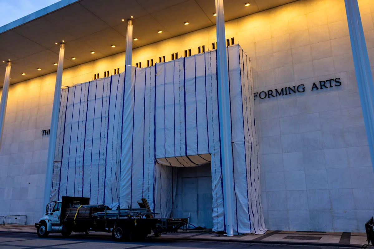 Uma equipe de trabalho ajusta a lona que cobre o andaime do Kennedy Center para permitir o acesso a uma grande porta em 13 de junho de 2026. / Crédito: Foto de Robb Hill/The Washington Post via Getty Images