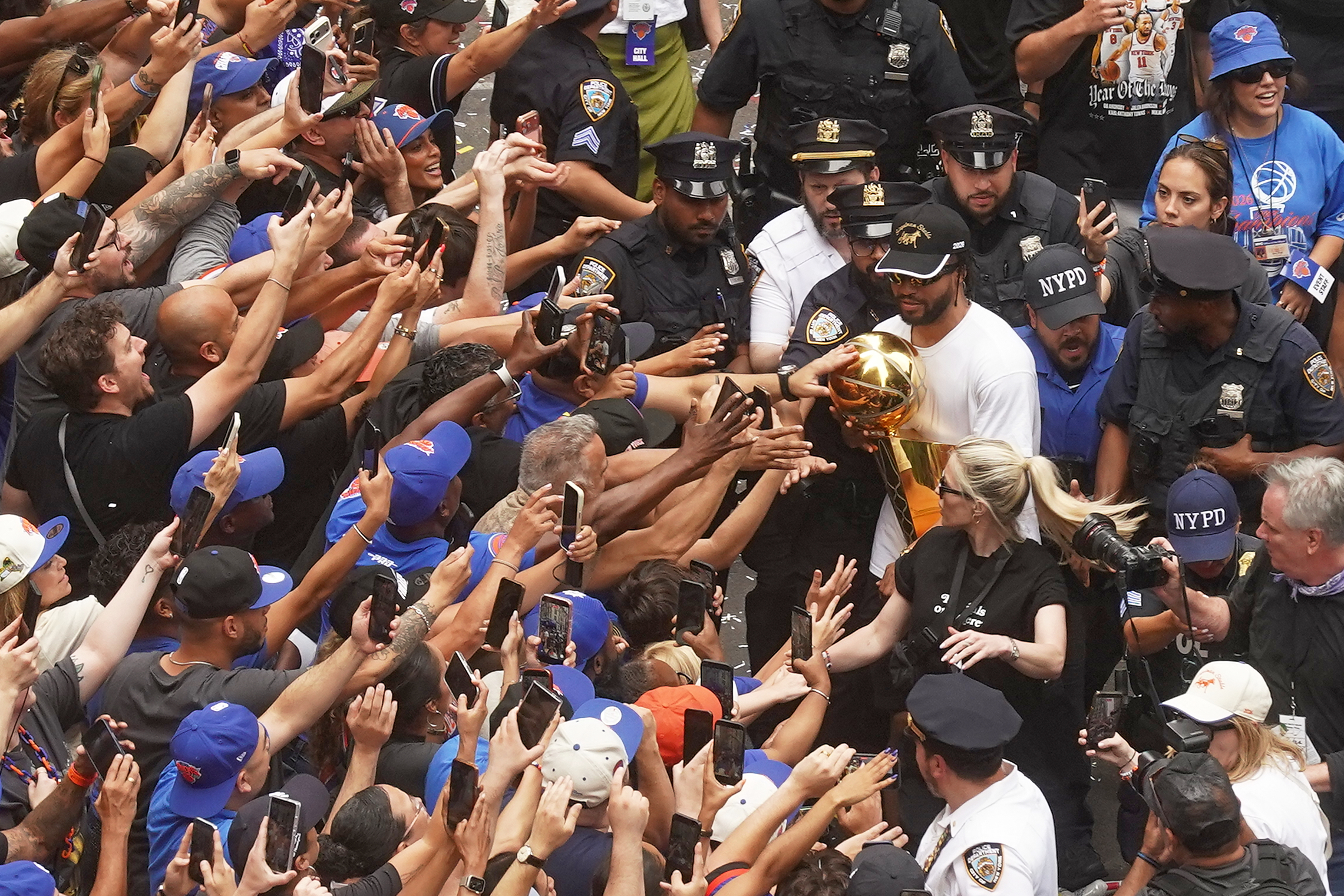 Jalen Brunson, no canto superior direito, do campeão da NBA New York Knicks carrega o troféu para os fãs durante o desfile na Broadway, em Nova York
