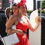 Mantendo a calma e seguindo em frente! Uma participante da corrida usa um ventilador para se refrescar ao chegar hoje ao Royal Ascot em Berkshire