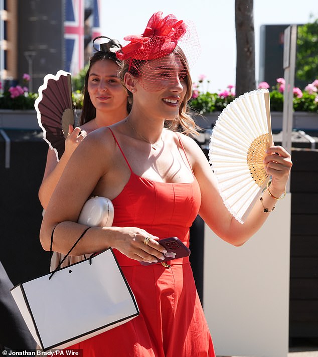 Mantendo a calma e seguindo em frente! Uma participante da corrida usa um ventilador para se refrescar ao chegar hoje ao Royal Ascot em Berkshire