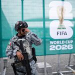 Um membro do coletivo Colectivo Luz de Esperanza de Jalisco segura panfletos de pessoas desaparecidas perto de cartazes colados com imagens de seus entes queridos que continuam desaparecidos, exibidos em formato de Copa do Mundo, como parte do “Álbum de Pessoas Desaparecidas da Copa do Mundo