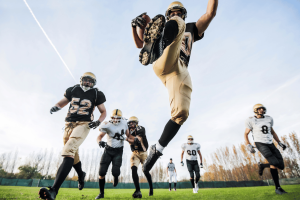 O jogador de futebol universitário salta para pegar um passe durante o jogo, enquanto o debate sobre apostas de jogadores da NCAA destaca as preocupações sobre o bem-estar dos atletas universitários e a integridade das apostas esportivas. NCAA e casas de apostas esportivas entram em conflito perante a Indiana Gaming Commission por causa de apostas em jogadores universitários