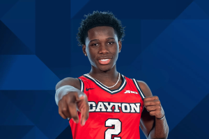 Jogador de basquete do Dayton Flyers com camisa vermelha nº 2 apontando para a câmera durante o retrato oficial do time. NCAA proíbe permanentemente Adam Njie após caso de compartilhamento de informações de apostas
