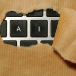 Não é só a Apple – o WhatsApp também precisa permitir IAs concorrentes | A imagem mostra as letras AI aparecendo através de uma capa de papel pardo
