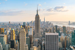 Vista panorâmica do horizonte da cidade de Nova York com o Empire State Building e os arranha-céus de Lower Manhattan durante o pôr do sol, destacando o centro financeiro e de entretenimento de Nova York. Nova York avança projeto de lei que exige extratos mensais de contas de apostas esportivas