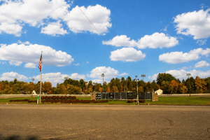 Saratoga Casino Hotel aproveita a pista de corrida em Saratoga Springs, Nova York, com placar, bandeira americana e área de backstretch sob um céu azul após revisão de segurança contra incêndio em celeiros em todo o estado.