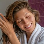 Mulher aplicando soro capilar no cabelo