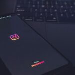 Os hackers enganaram a Meta AI para deixá-los assumir o controle de contas de alto perfil | Foto discreta mostra a abertura do aplicativo em um smartphone colocado em cima de um teclado MacBook