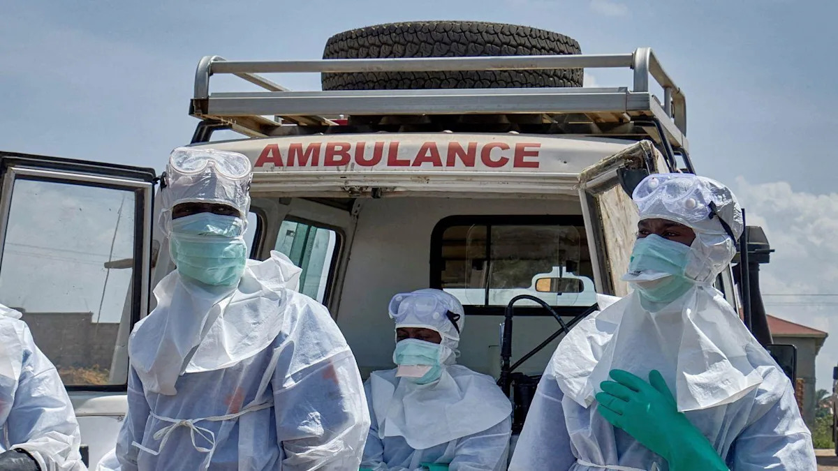 Dois profissionais de saúde são fotografados usando equipamento de proteção azul