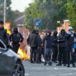 Uma moradora olha para os destroços carbonizados espalhados nas ruas de seu bairro, após protestos anti-imigrantes após um ataque com faca em 8 de junho, que deixou um homem gravemente ferido e levou a polícia a declarar um incidente crítico, na rua Lendrick, leste de Belfast, Irlanda do Norte, 10 de junho de 2026. REUTERS/Isabel Infantes
