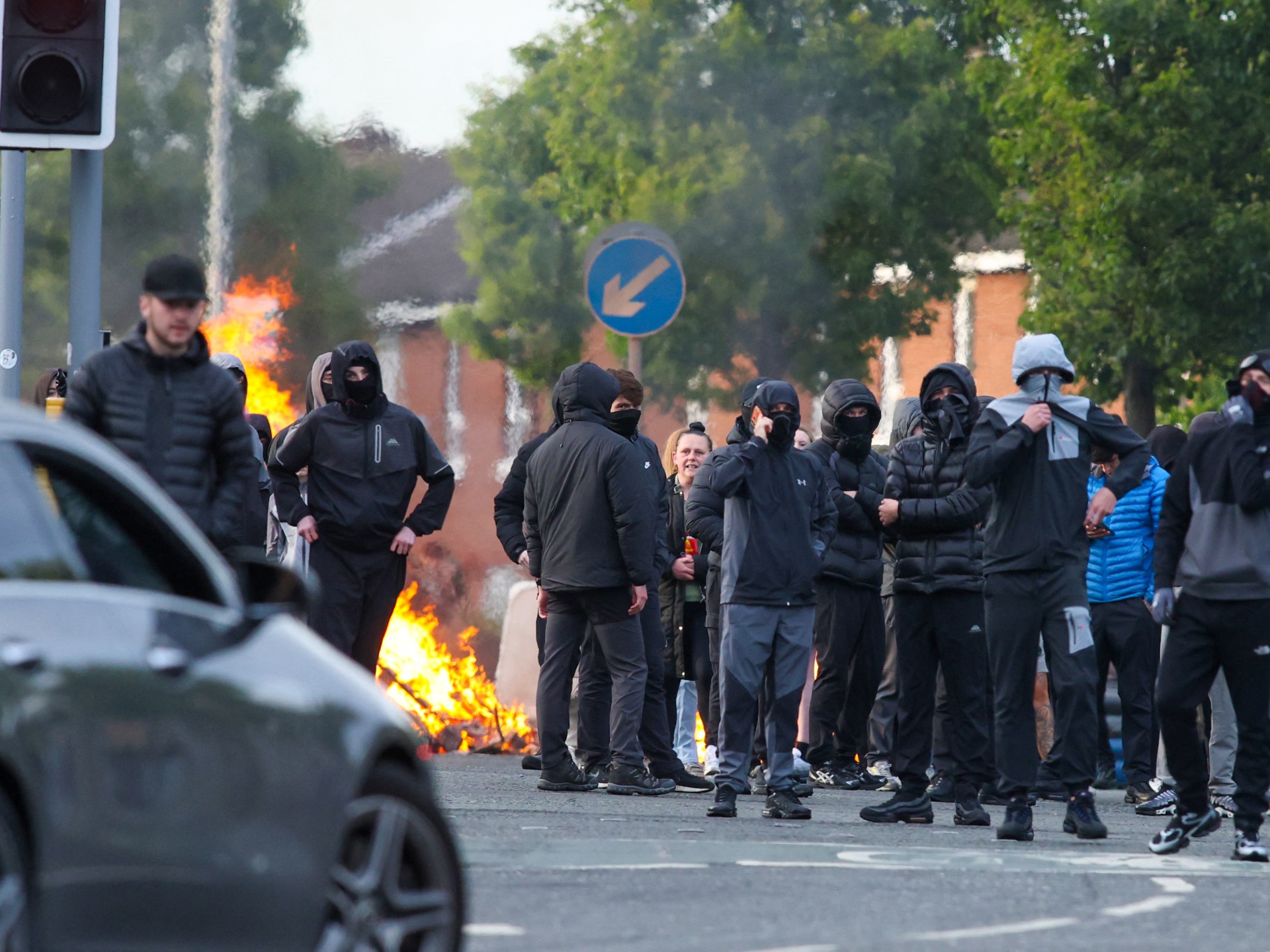 Uma moradora olha para os destroços carbonizados espalhados nas ruas de seu bairro, após protestos anti-imigrantes após um ataque com faca em 8 de junho, que deixou um homem gravemente ferido e levou a polícia a declarar um incidente crítico, na rua Lendrick, leste de Belfast, Irlanda do Norte, 10 de junho de 2026. REUTERS/Isabel Infantes