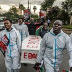 Trabalhadores da Cruz Vermelha enterram uma vítima do Ebola no Cemitério Rwampara, em Bunia, Congo, sábado, 23 de maio de 2026. (AP Photo/Moses Sawasawa)