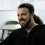 A caucasian man with long dark hair and a full beard