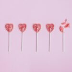 Five lollipop hearts on a pink floor, but the last one is smashed to pieces.