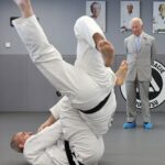 Um fascinado Rei Charles observa - usando galochas protetoras - enquanto assiste a uma partida de Jiu Jitsu durante uma visita ao oeste de Londres para saber mais sobre a instituição de caridade Reorg