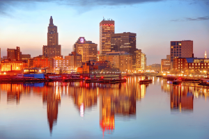 O horizonte de Rhode Island ao pôr do sol refletido no rio Providence, destacando o centro de Providence enquanto os legisladores consideram expandir o mercado de apostas esportivas do estado e acabar com seu monopólio de apostas esportivas.