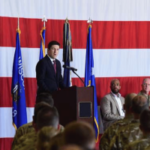 Steil apresenta projeto de lei que restringe as negociações no mercado de previsão do Congresso. O deputado Bryan Steil discursa em um evento militar diante de militares e oficiais, em um pódio em frente a uma grande bandeira americana enquanto discute a política do Congresso e as reformas éticas do governo.