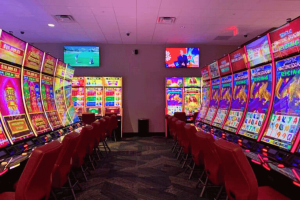 Vista interna do Two Coppers Casino em Juneau, Alasca, com fileiras de máquinas de jogos eletrônicos, cadeiras vermelhas, displays de caça-níqueis brilhantes e telas de televisão suspensas durante a inauguração do cassino.