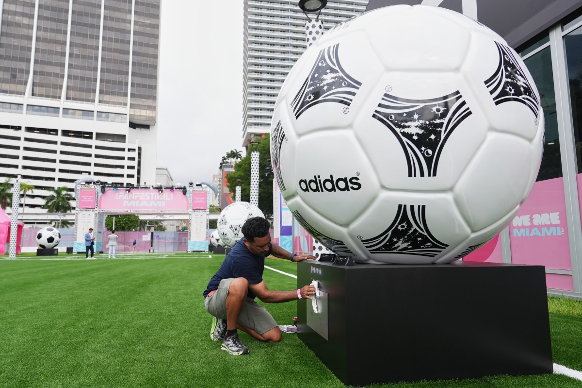 Jorge Gonzalez cleans a display featuring giant soccer balls, replicas from former World Cup tournaments, during a media preview of a Fan Festival for the World Cup soccer tournament, Wednesday, June 10, 2026, at Bayfront Park in Miami.