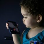 A Apple deve continuar a verificar a idade dos usuários no Texas, diz decisão de uma frase | A foto mostra uma criança muito pequena fazendo uma ligação em um iPhone