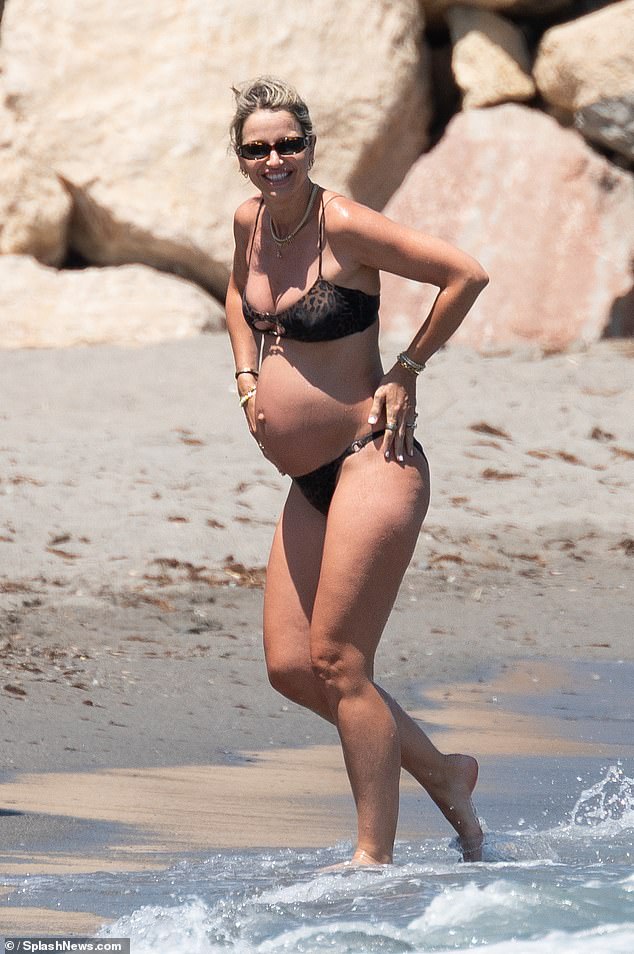 A grávida Vogue Williams, 40, exibiu sua barriga em um biquíni com estampa de leopardo ao chegar à praia na Espanha na segunda-feira