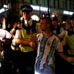 Polícia em Londres escolta um torcedor argentino para longe dos torcedores ingleses após o apito final