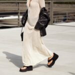 BERLIM, ALEMANHA - 27 DE MAIO: Lisa Mottl é vista vestindo um blazer oversized trespassado esbranquiçado com lapelas largas e afiadas, ombros acolchoados, mangas compridas, duas fileiras paralelas de botões forrados de tecido combinando e bolsos clássicos com aba horizontal da Bazhane; um top branco da Zara; calças capri cortadas em marrom camelo com presilhas para cinto, bolsos com abas angulares, pernas largas e fluidas e bainhas ajustáveis ​​com cordão criando uma silhueta franzida em forma de balão da Zara; couro esbranquiçado