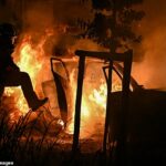 Um bombeiro borrifa água em carros em chamas durante um incêndio em frente a um acampamento em Villeneuve-les-Beziers, no sul da França