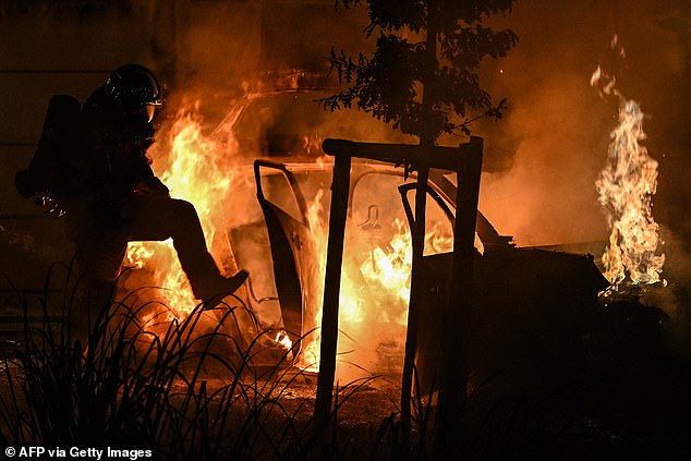 Um bombeiro borrifa água em carros em chamas durante um incêndio em frente a um acampamento em Villeneuve-les-Beziers, no sul da França