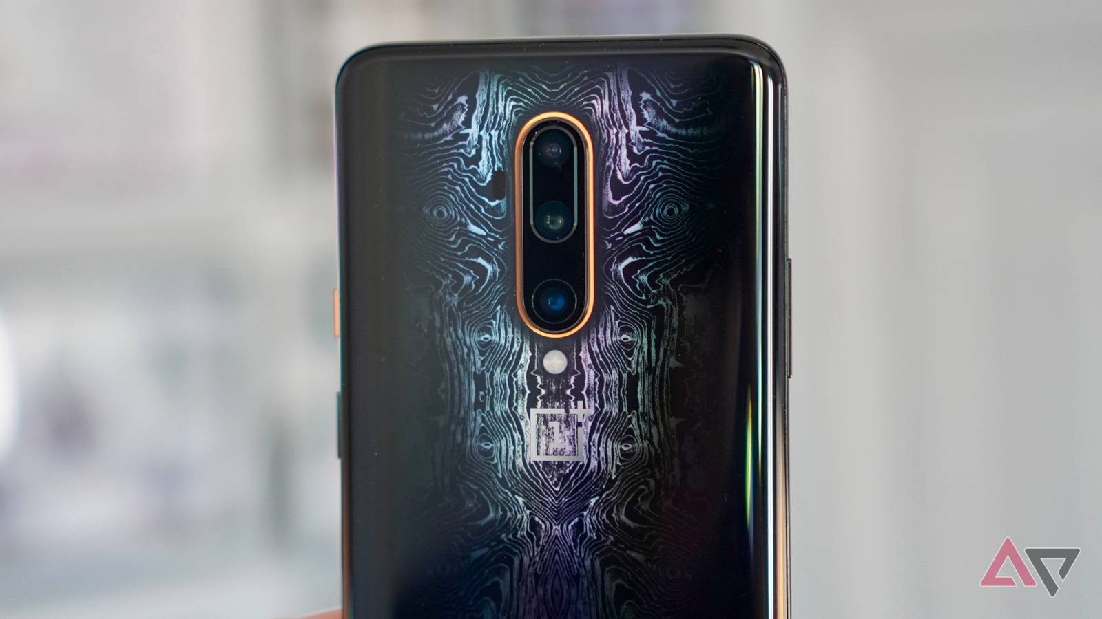 Smartphone OnePlus 16 flutuando na frente de um '16' azul brilhante, cercado por partículas de cinzas e fumaça leve.