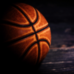 Close de uma bola de basquete em uma quadra de madeira ilustrando a investigação de apostas da NBA, jogos de azar, manipulação de resultados e investigação federal de corrupção. Doze réus preparam confissões de culpa em caso de fraude de pôquer fraudulento relacionado à NBA