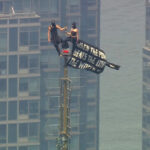 WABC - FOTO: Duas pessoas exibem um banner após subirem ao topo da antena do Empire State Building na cidade de Nova York, 1º de julho de 2026.