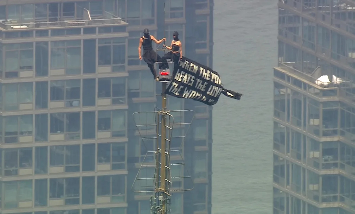 WABC - FOTO: Duas pessoas exibem um banner após subirem ao topo da antena do Empire State Building na cidade de Nova York, 1º de julho de 2026.