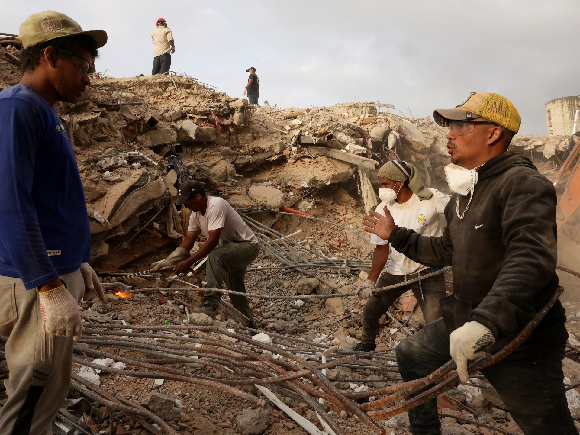 Pessoas trabalham juntas enquanto procuram seus entes queridos em meio aos escombros, após os terremotos de 24 de junho, em Caraballeda, em La Guaira, Venezuela, em 19 de julho de 2026. REUTERS/Gaby Oraa