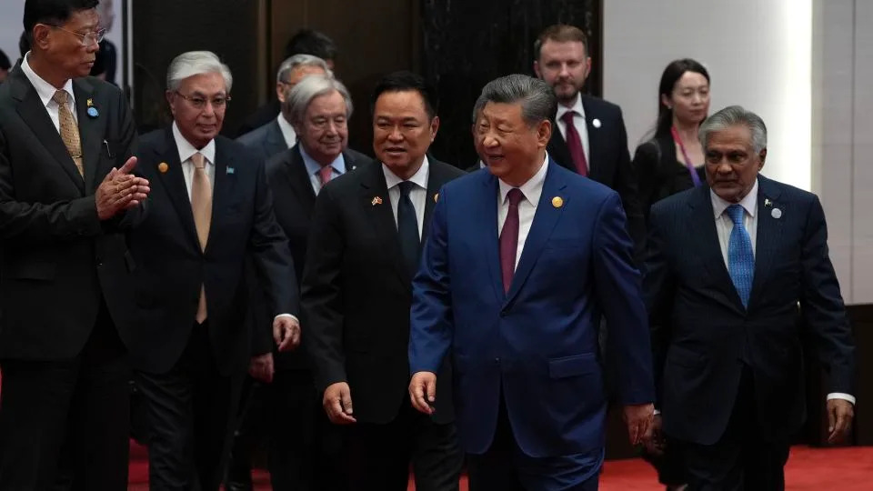Um visitante posa para um amigo em frente a um outdoor mostrando um robô humanóide na Exposição Internacional da Cadeia de Fornecimento da China, em Pequim, no mês passado. -Kevin Frayer / Imagens Getty