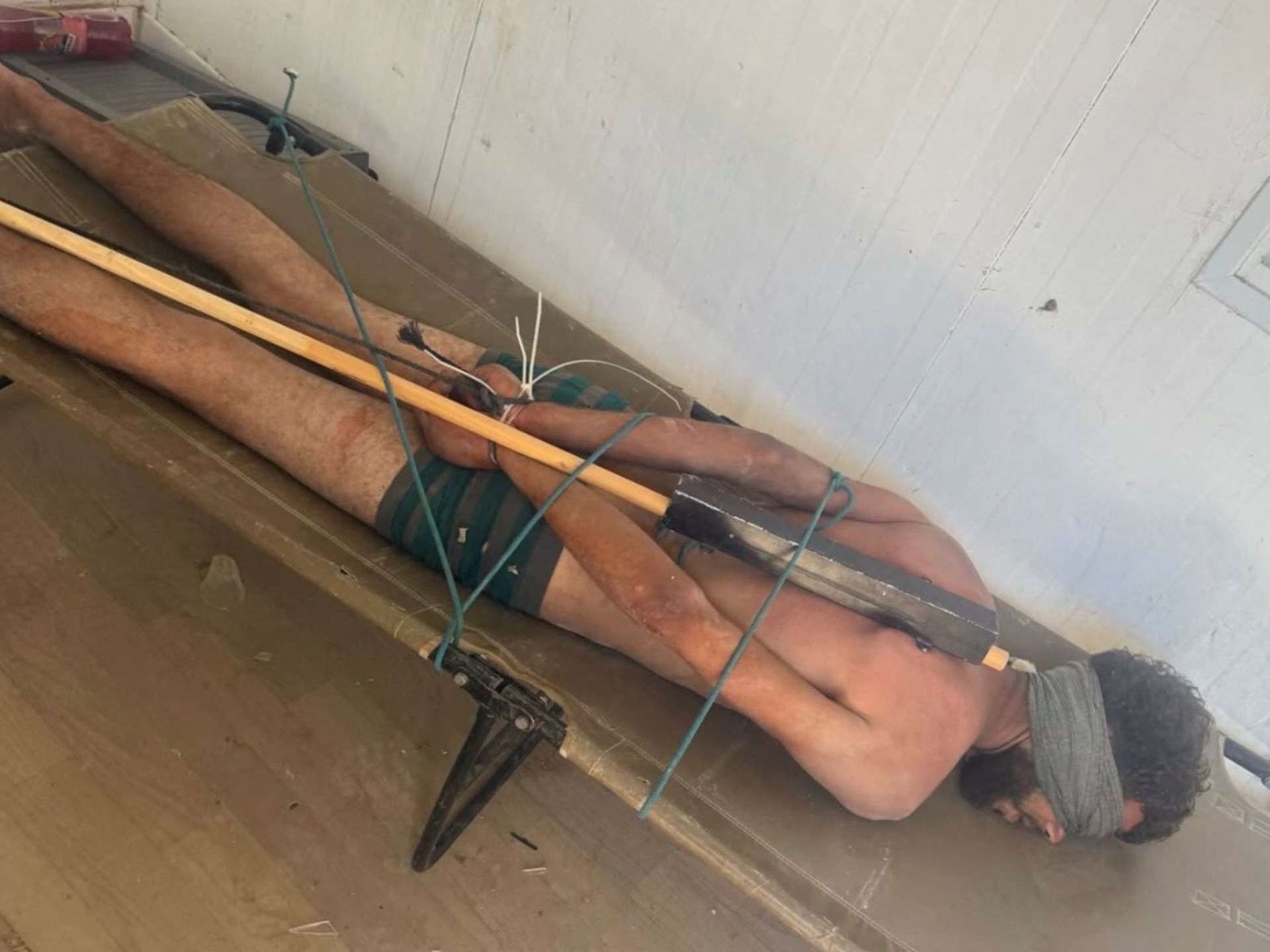 Rana Abu Nassar, mãe do prisioneiro palestino Osama Abu Nassar, detido por Israel, segura um celular exibindo uma imagem amplamente divulgada que ela acredita mostrar seu filho contido enquanto estava sob custódia israelense, em sua casa no campo de refugiados de Al-Maghazi, no centro da Faixa de Gaza, em 3 de julho de 2026. A imagem desencadeou uma busca desesperada pela identidade do homem, com duas famílias palestinas reivindicando-o como seu filho. REUTERS/Mahmoud Issa