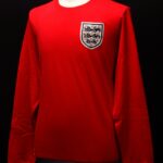 Em 1966, o uniforme visitante da Inglaterra, fabricado pela Umbro, era vermelho, branco e marinho e tinha mangas compridas