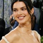 Uma mulher adulta concentrada pratica automassagem facial em seu banheiro bem iluminado. Usando as pontas dos dedos, ela suaviza suavemente a pele para melhorar a circulação, reduzir a tensão e promover um brilho saudável e natural. Este autêntico momento de bem-estar em casa captura a tendência popular de beleza e autocuidado