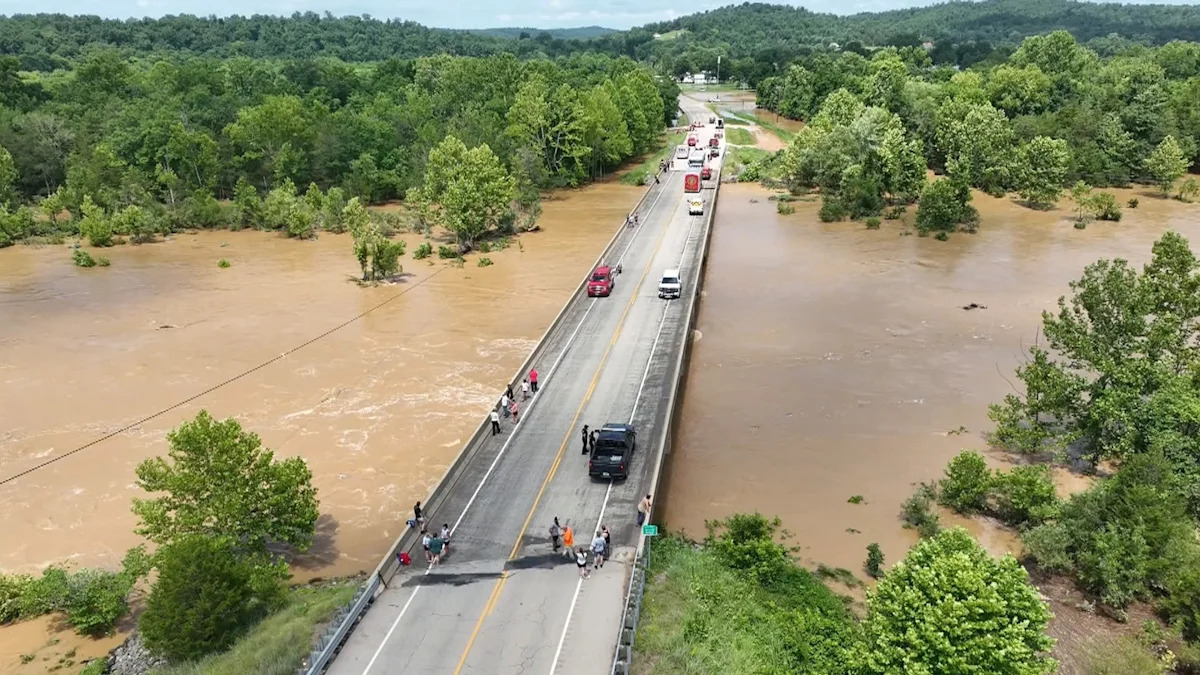 Heartland News - FOTO: Pessoas ficam em uma ponte acima das enchentes do Rio Black em Lesterville, Missouri, 10 de julho de 2026.