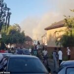 Moradores observam depois que um grande incêndio eclodiu perto da Vallentin Road, em Walthamstow, ontem