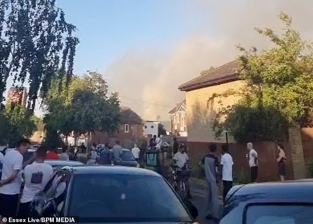 Moradores observam depois que um grande incêndio eclodiu perto da Vallentin Road, em Walthamstow, ontem