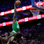 Neemias Queta, do Boston Celtics, no topo, sobe para uma enterrada sobre Kelly Oubre Jr., do Philadelphia 76ers, à direita, e Joel Embiid durante a primeira metade do jogo 4 em uma primeira rodada de basquete da NBA